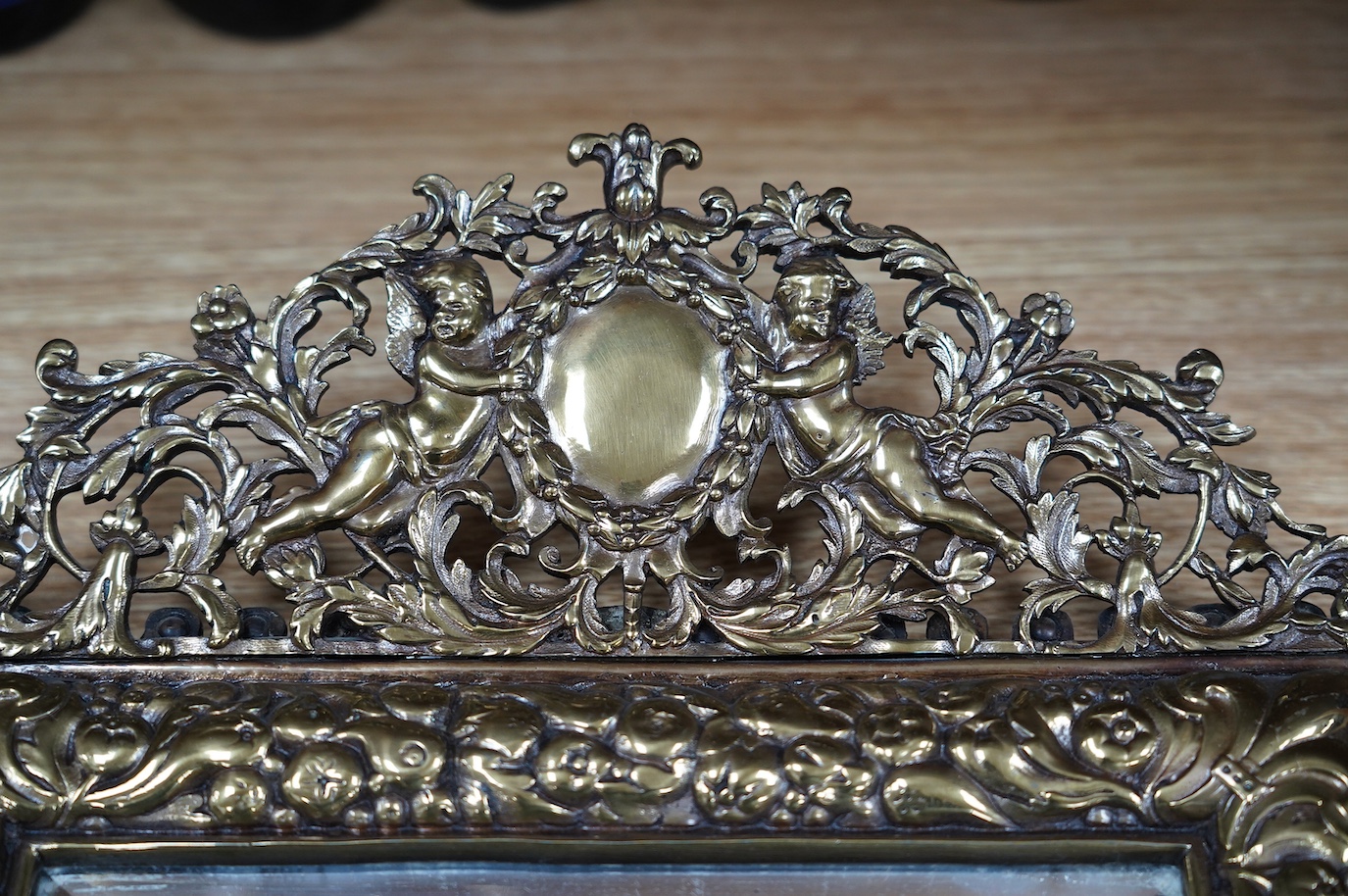 A pair of French brass repoussé mirrors with an ornate putti top and mask decorated bottom, 49cm high. Condition - good